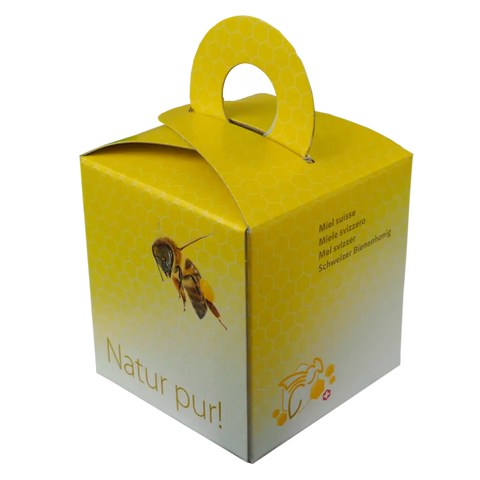 Gelbe Geschenkbox aus Karton mit  Alpenhonig 500g geschlossen mit Tragegriff und Wabenmuster und dem Aufdruck einer Biene und Natur pur!